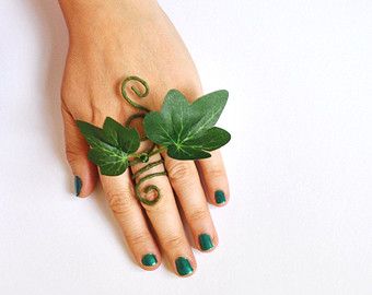 a woman's hand with green manicures and leaves on her fingers, against a white background