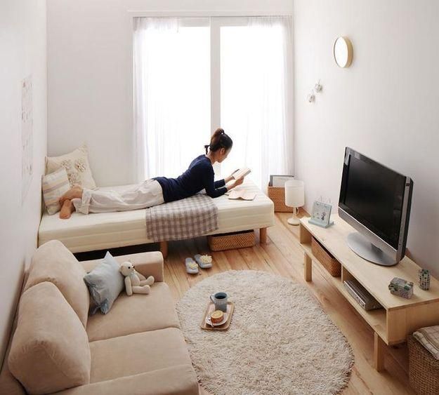 a woman is laying on the couch in her living room reading a book and watching tv