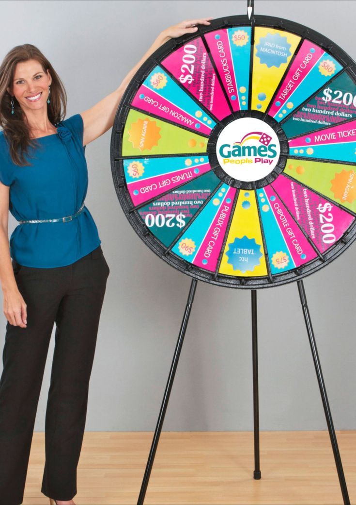 a woman standing next to a giant wheel of fortune game with $ 200 on it