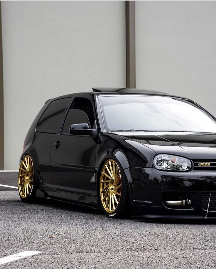 a black car with gold rims parked in front of a building