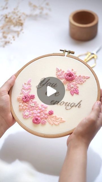 a person is holding a cross - stitch hoop with flowers on it and the words laugh through