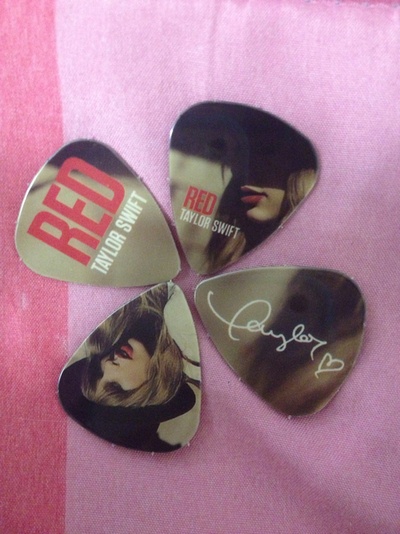 three guitar picks with the words bee gee on them sitting on a pink and white blanket