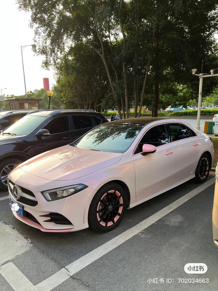 a white car parked in a parking lot next to another car with pink ribbon on it