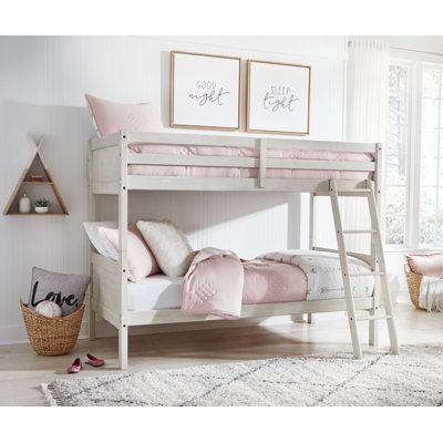 a white bunk bed with pink pillows and blankets on top of it, next to a window