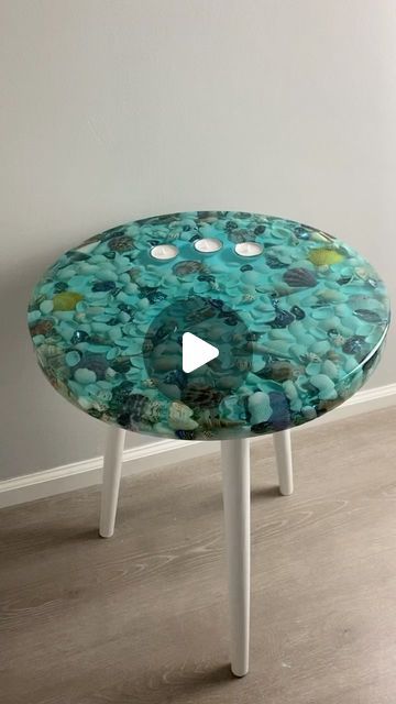 a glass table with holes in the center and white legs, on top of a hard wood floor