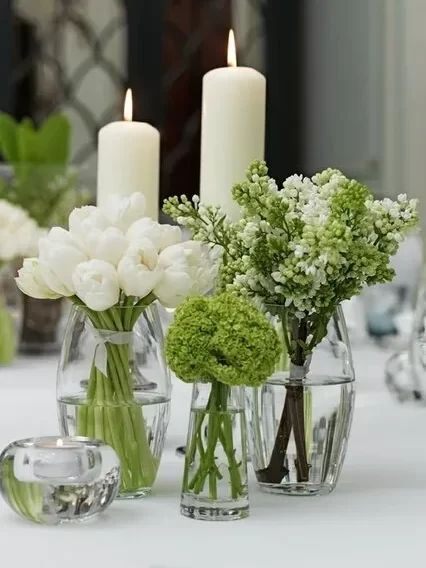 three vases with flowers and candles on a table