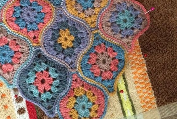 a crocheted blanket is laying on the floor