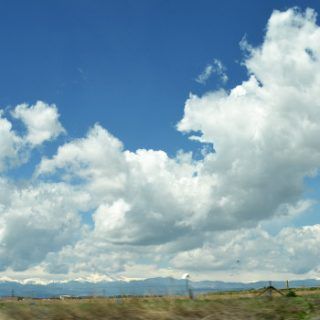 the sky is filled with fluffy clouds as seen from a moving car on a highway