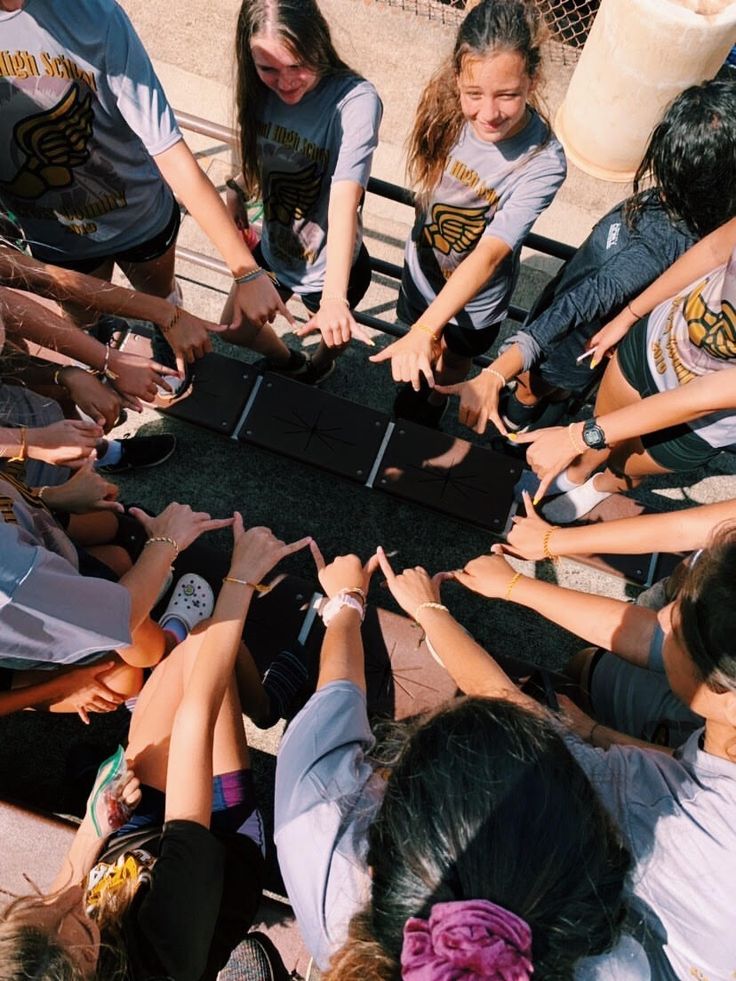 a group of young people standing around a table with their hands in the center and one person reaching for something