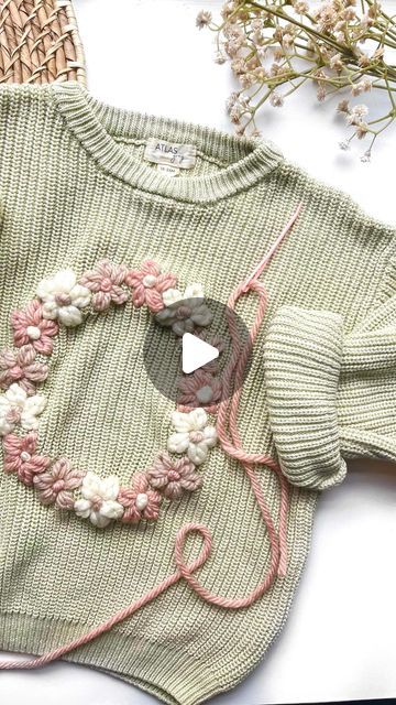 a sweater with flowers on it next to some yarn