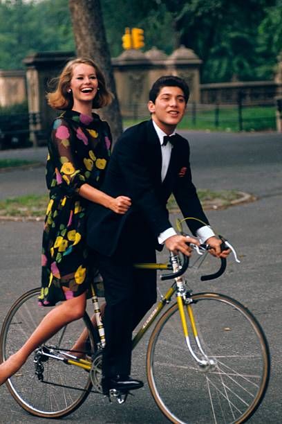 a man and woman riding on the back of a bike