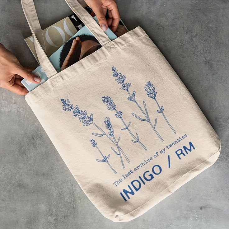 a person holding a tote bag with an image of lavenders on it and the words indigoo / rm