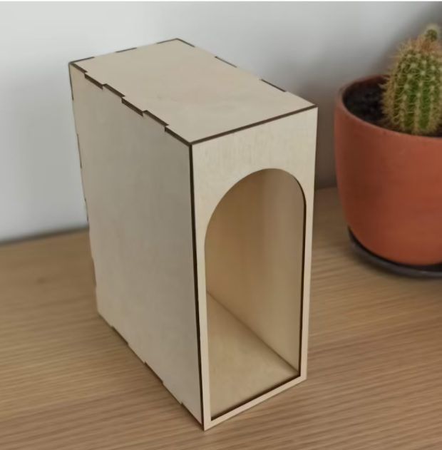 a small wooden box with a hole in it next to a potted cacti