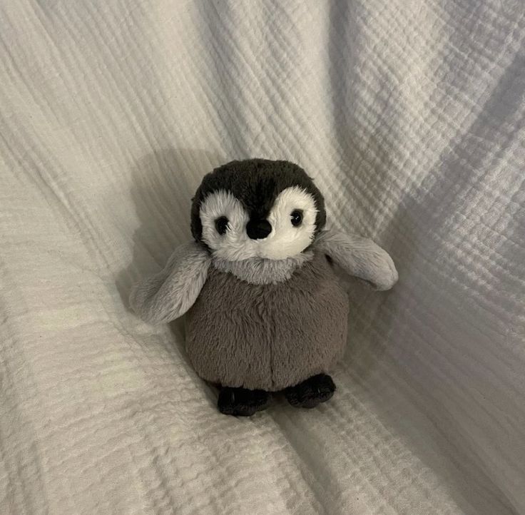 a small stuffed penguin sitting on top of a bed