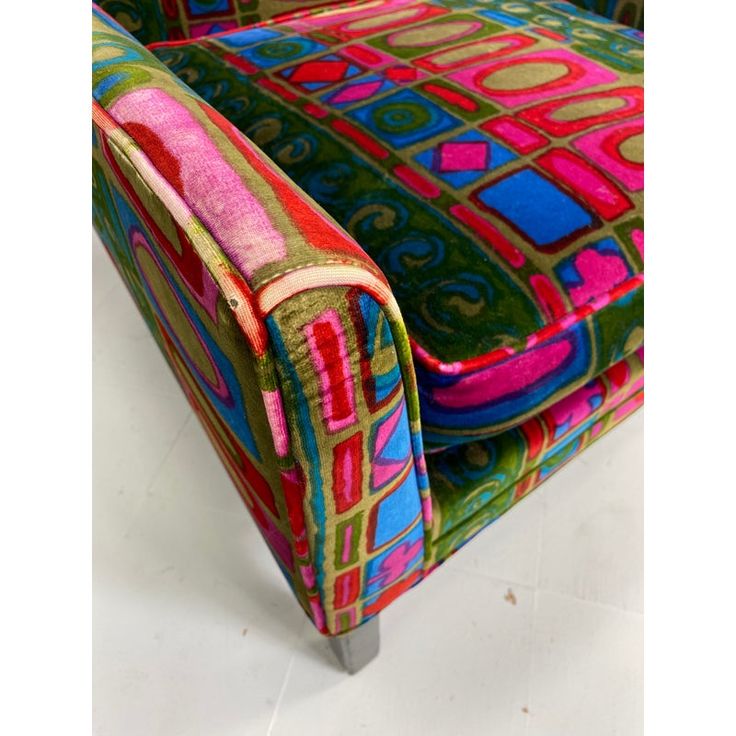 an upholstered chair with colorful fabric on it