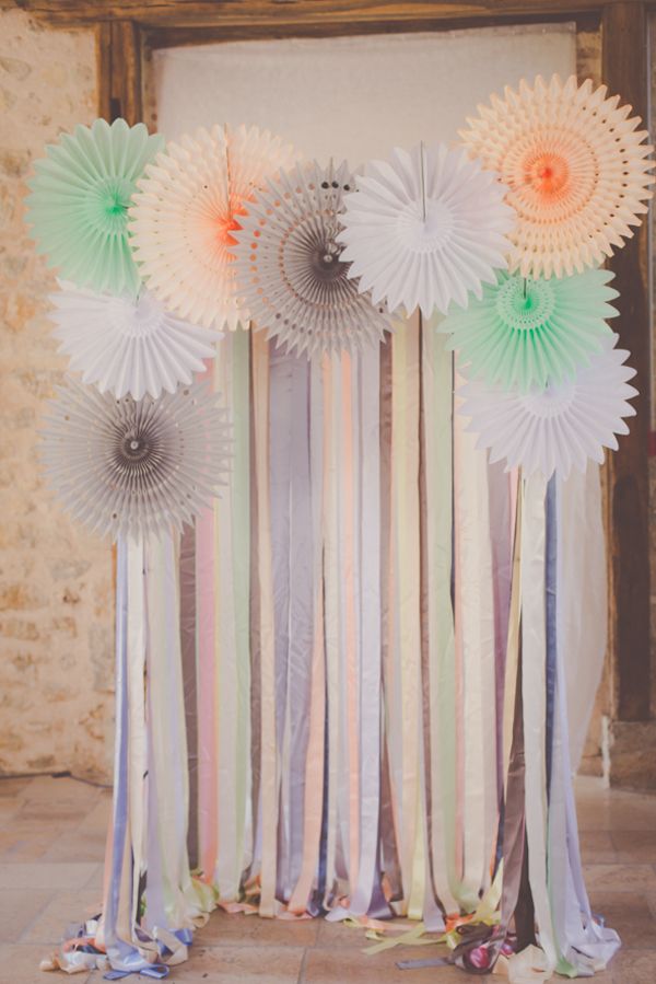some paper fans are hanging on the wall in front of a door with ribbons and streamers