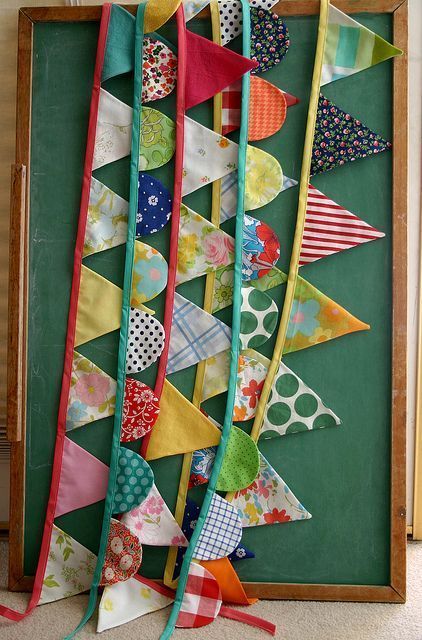 several colorful flags are hanging on a green wall in front of a blackboard with an old wooden frame