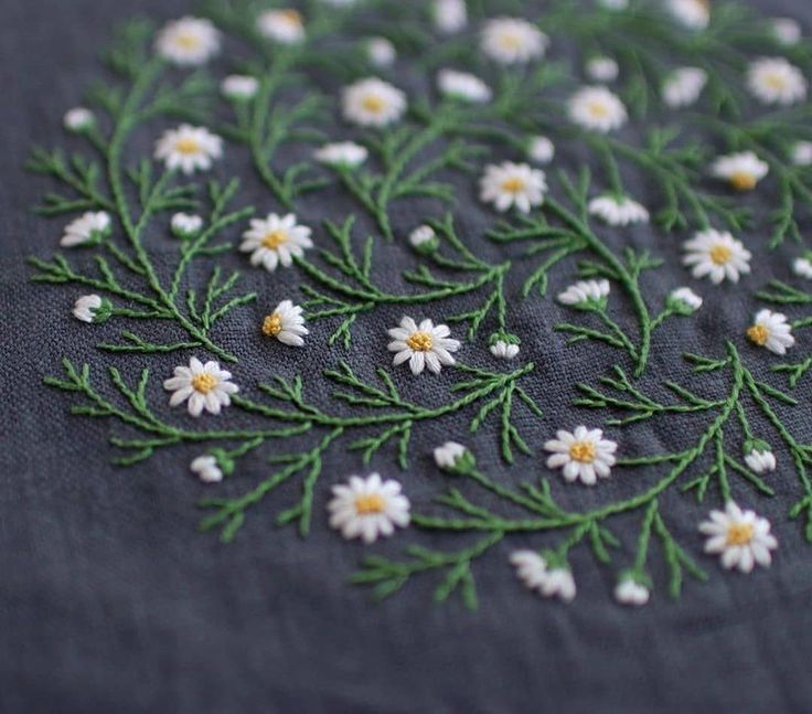 a close up of a piece of cloth with daisies on it and green stems
