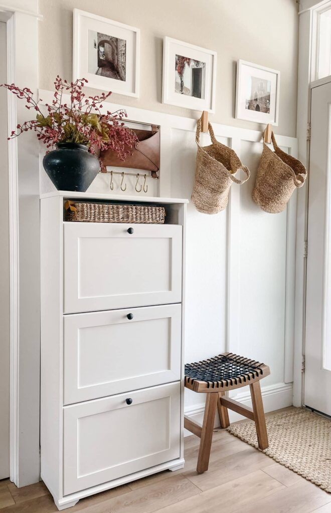 a white cabinet with two baskets on it and pictures hanging above the drawers in front of it