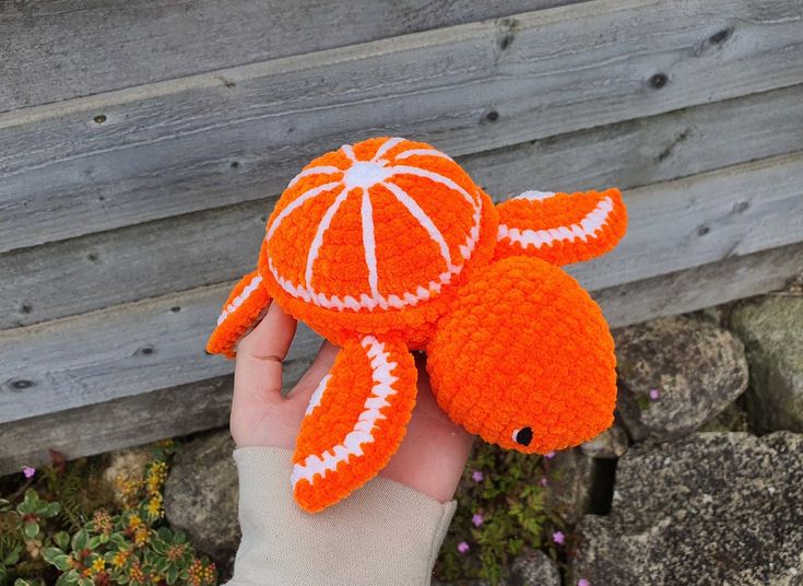 someone is holding an orange stuffed animal in their left hand and it looks like they are made out of crochet