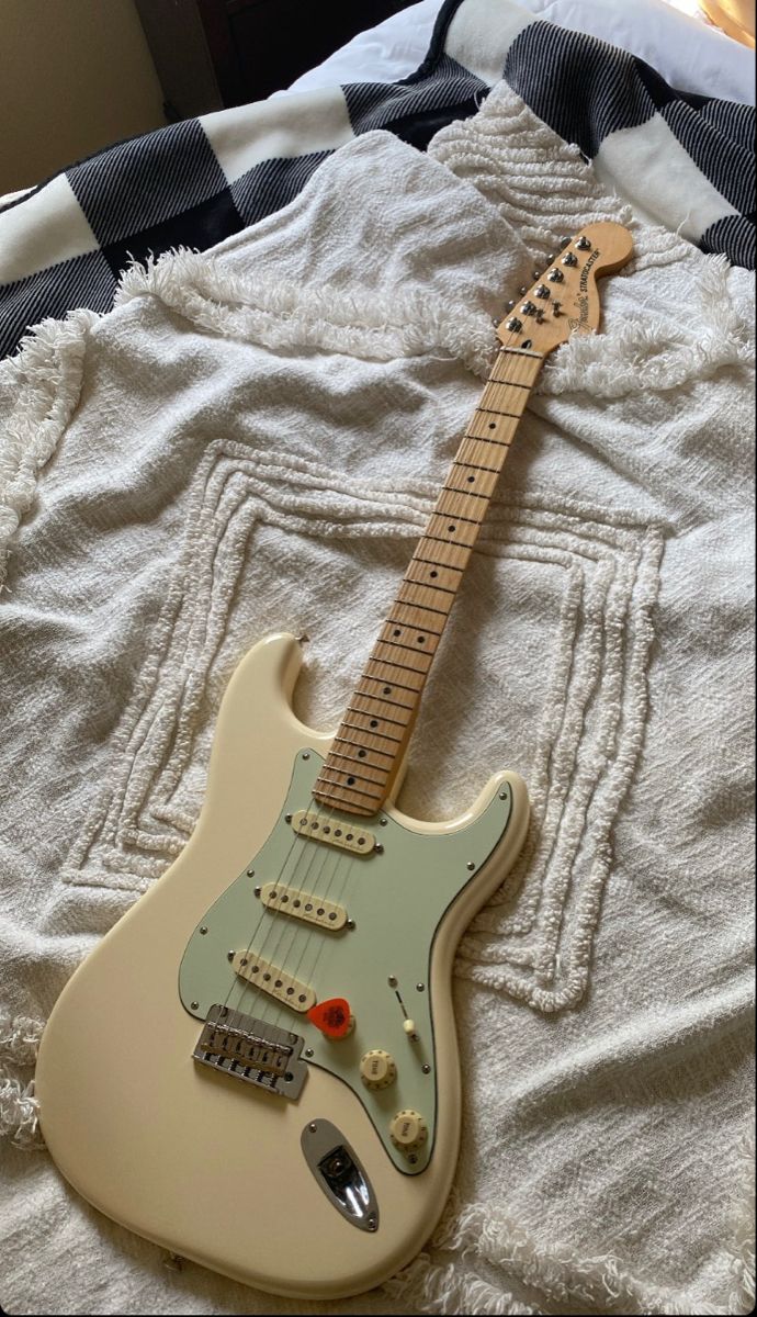 an electric guitar sitting on top of a bed