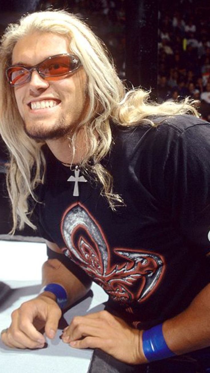 a man with long blonde hair and sunglasses sitting at a table
