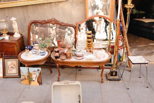 antique furniture and other antiques are on display in front of a building with an old mirror