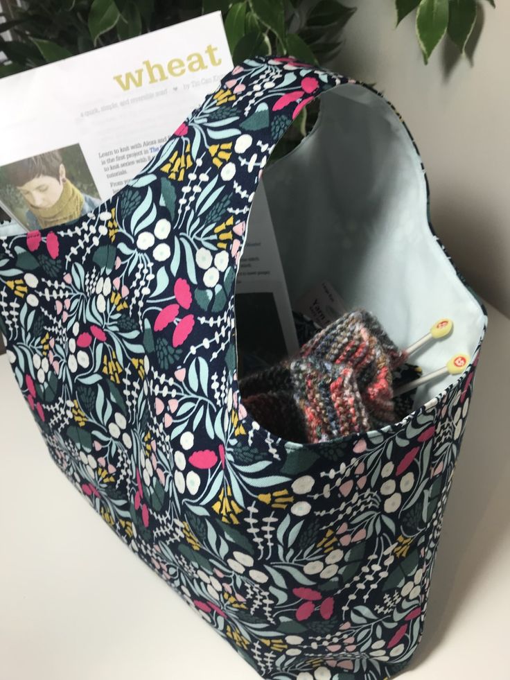 an open fabric bag sitting on top of a table next to a potted plant