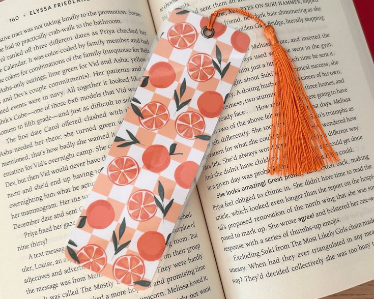 an open book with oranges on it and a tassel hanging from the cover