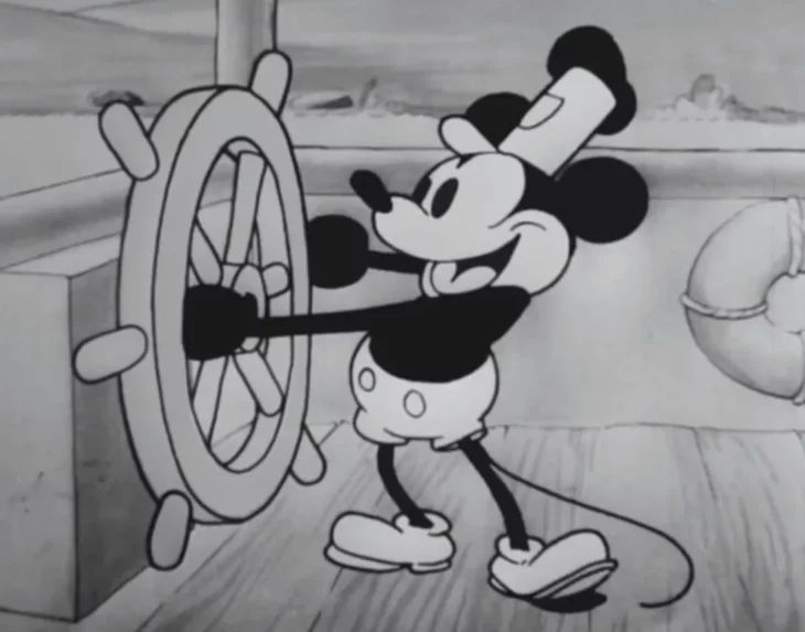 the mickey mouse cartoon is standing next to a wheel and holding onto it's hand