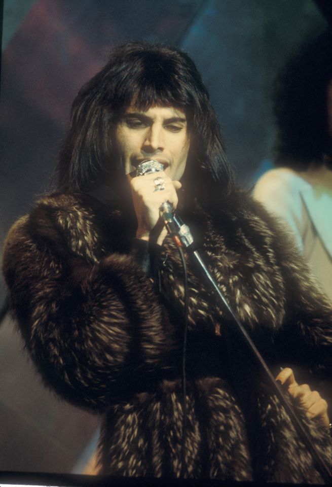 a man in a fur coat singing into a microphone