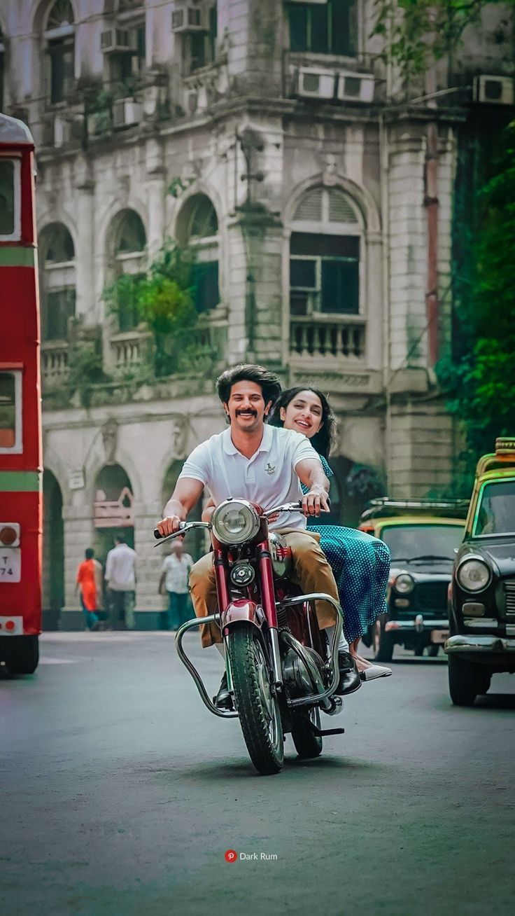 a man and woman riding on the back of a motorcycle