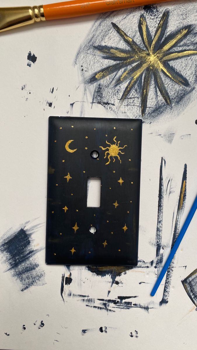 a light switch cover sitting on top of a table next to paintbrushes and pencils