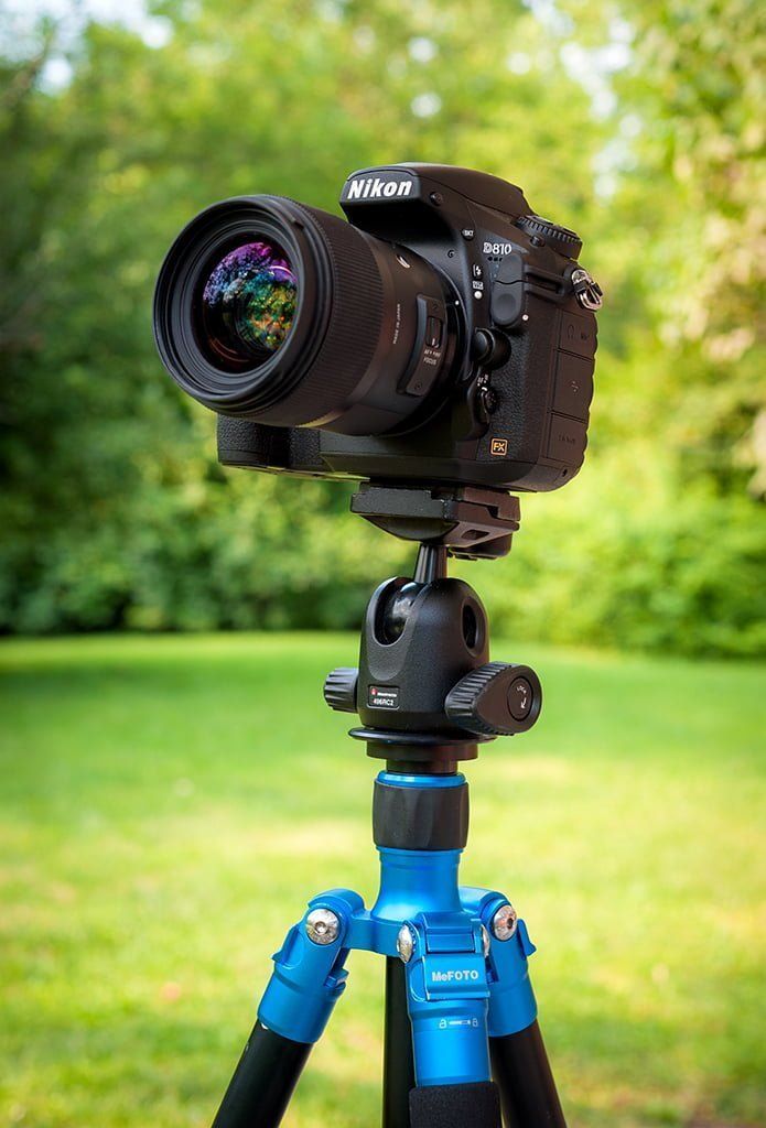 a camera is sitting on top of a tripod in front of some grass and trees