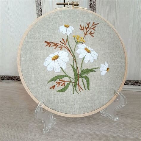 a cross - stitched white flower with green leaves on it sits in front of a door