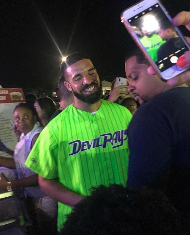 a man in a green jersey is holding up his cell phone to take a photo