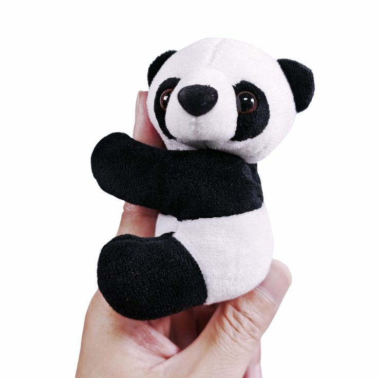 a hand holding a black and white stuffed panda bear