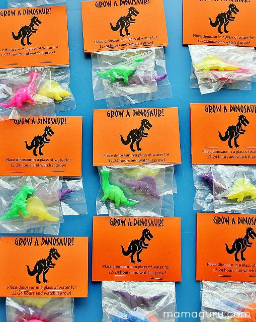 there are many different colored dinosaurs in plastic bags on the table with orange and green tags