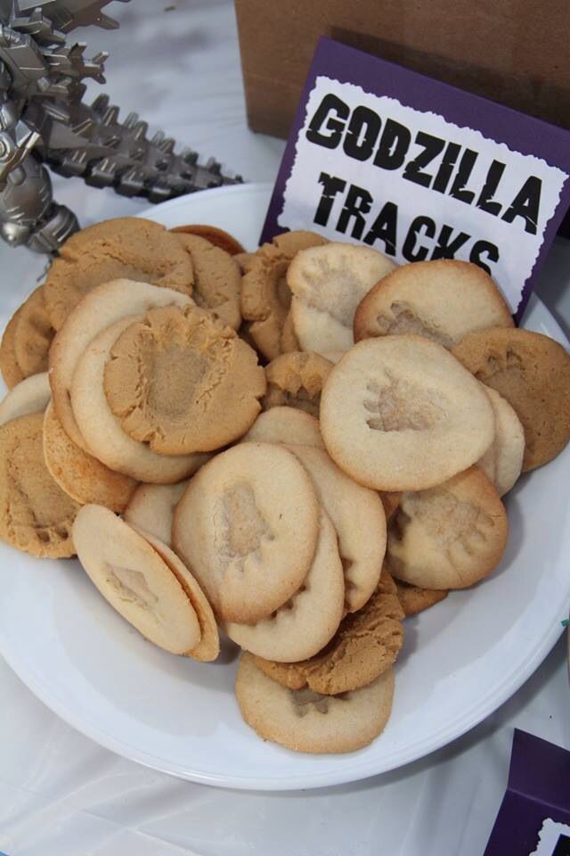 cookies are arranged on a white plate with a sign that says godzilla tracks in the middle