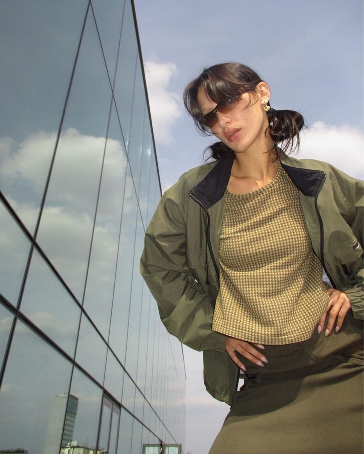 a woman standing in front of a building with her hands on her hips and looking at the camera