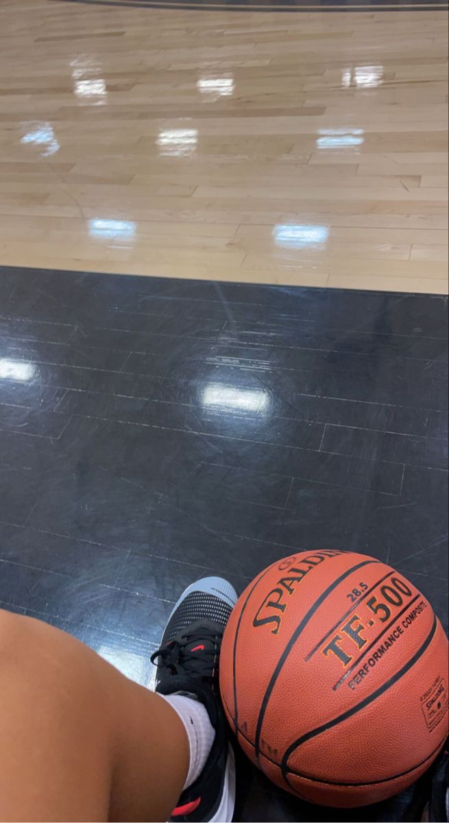 a person sitting on the floor with a basketball in front of them and their feet propped up next to it