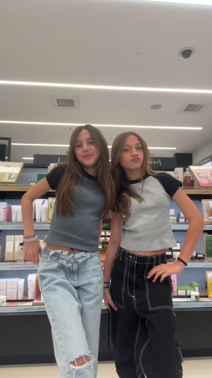 two girls are standing in front of the counter at a store with their hands on their hips