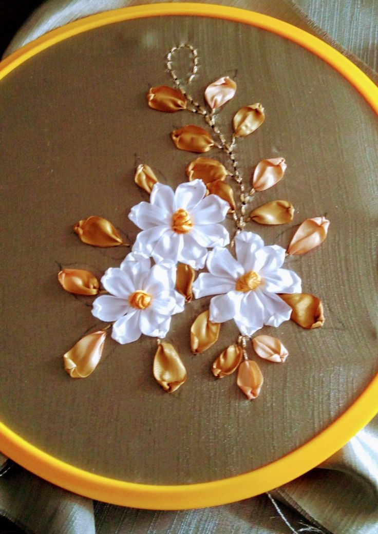 an embroidery project with white flowers and gold leaves