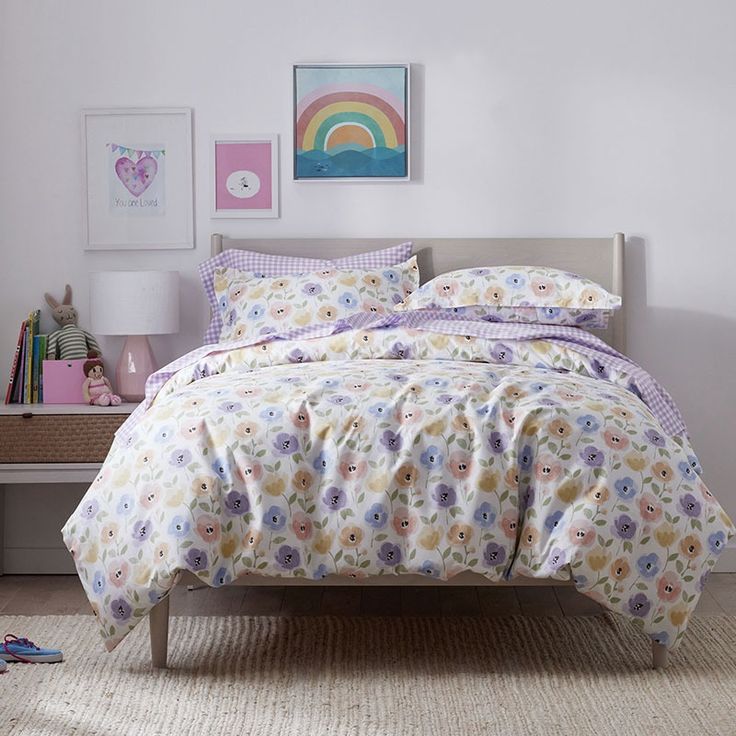 a bed with flowers on it in a bedroom next to a table and pictures hanging on the wall