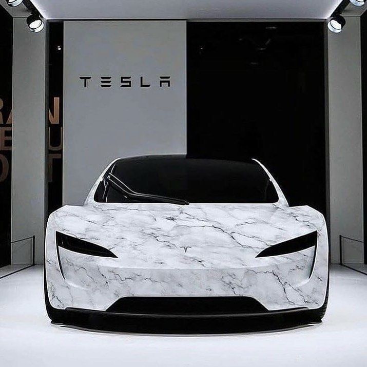 an electric car on display in front of a black and white wall with the tesla logo