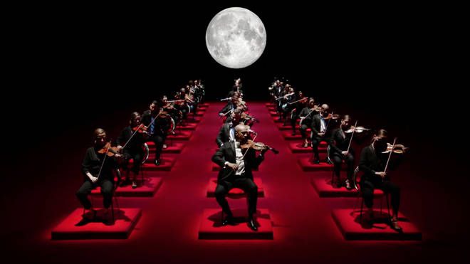 a group of men in suits and ties playing instruments on stage with the moon behind them