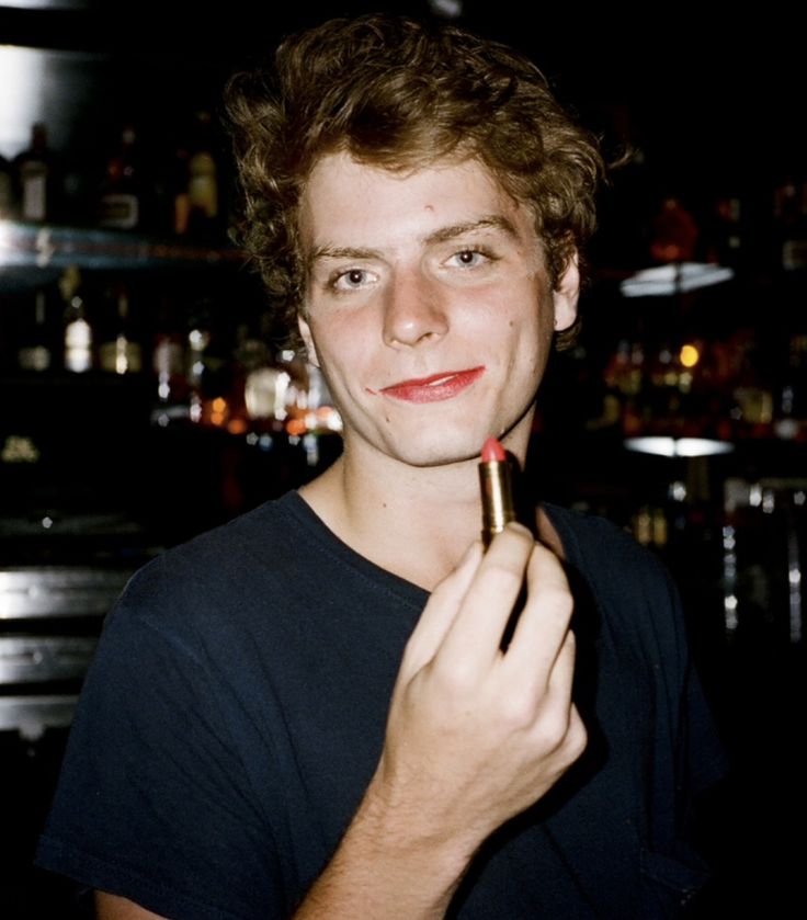 a young man is holding a lipstick in his hand