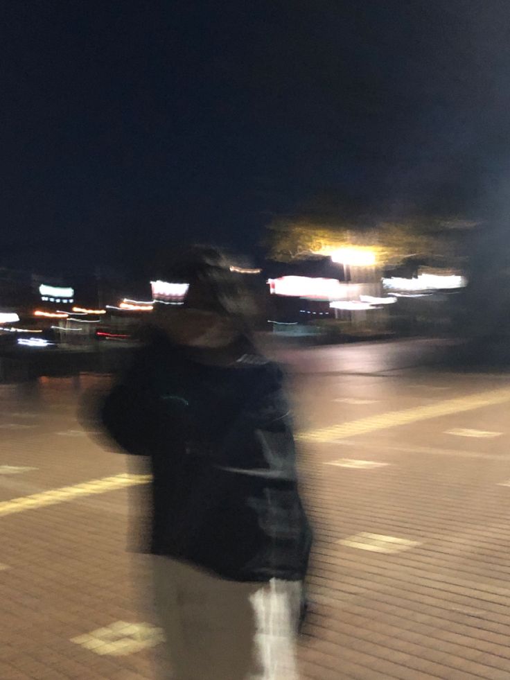 a blurry image of a person riding a skateboard on the street at night