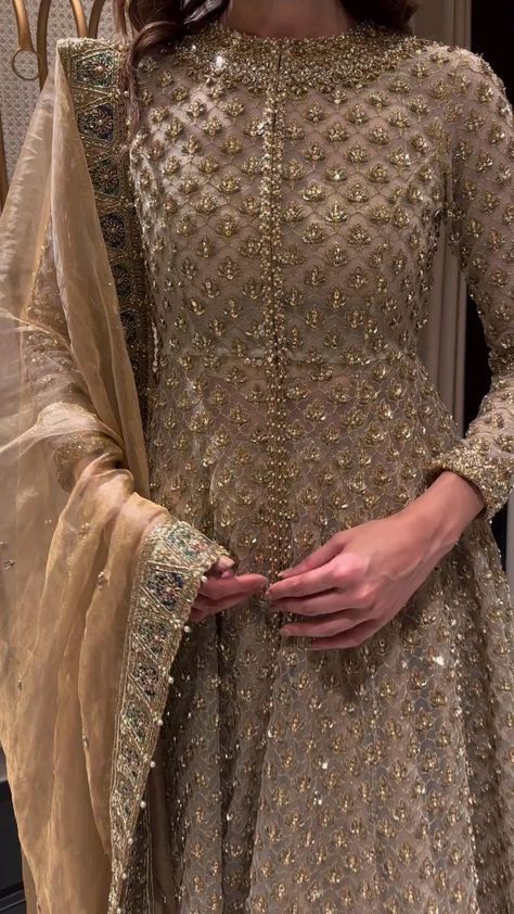 a woman in a beige outfit standing next to a mirror