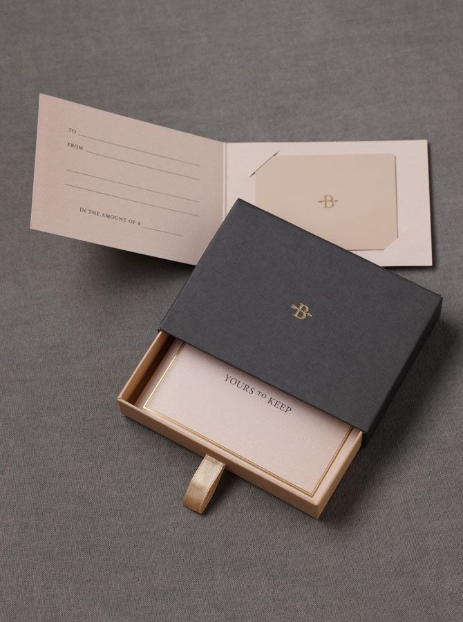 an open box with a card inside on a table next to a piece of paper